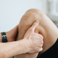 Close-up of a physiotherapist massaging a patient's knee during therapy.