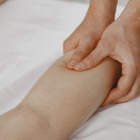 Close-up image of a massage therapist applying pressure on a client's leg for muscle relaxation.
